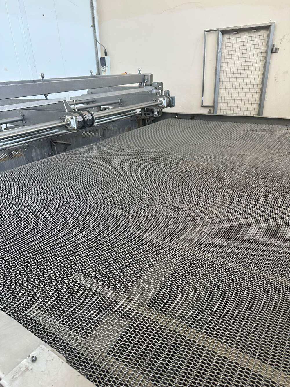 New woven wire band spread across the oven infeed