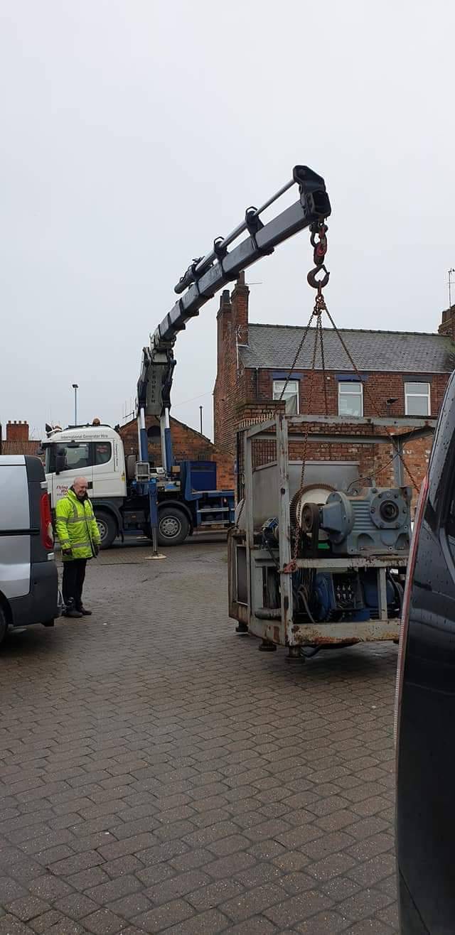 Crane lifting production machinery during an installation