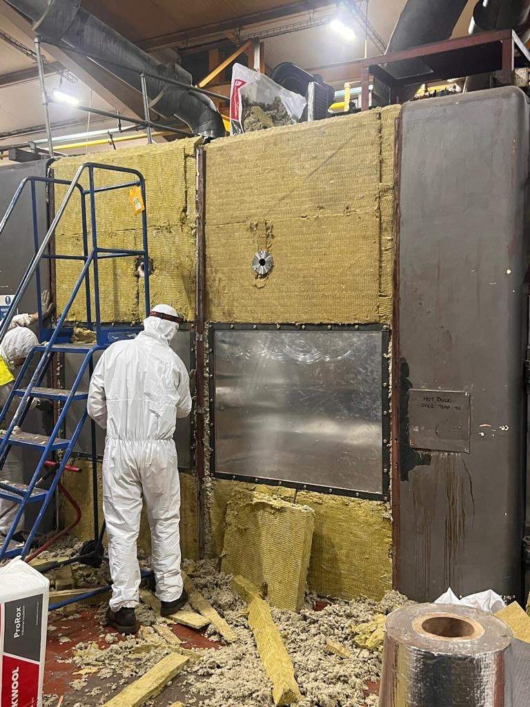 Old insulation being stripped from the oven casing